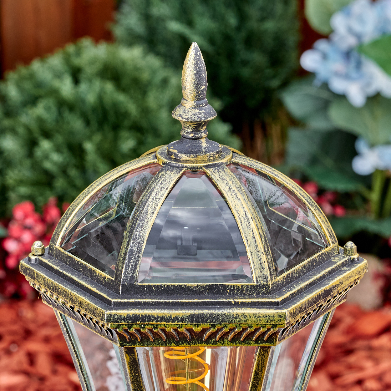 Ein goldener und schwarzer Laternenkopf mit Glasfenstern und einem spitzen oberen Abschluss.