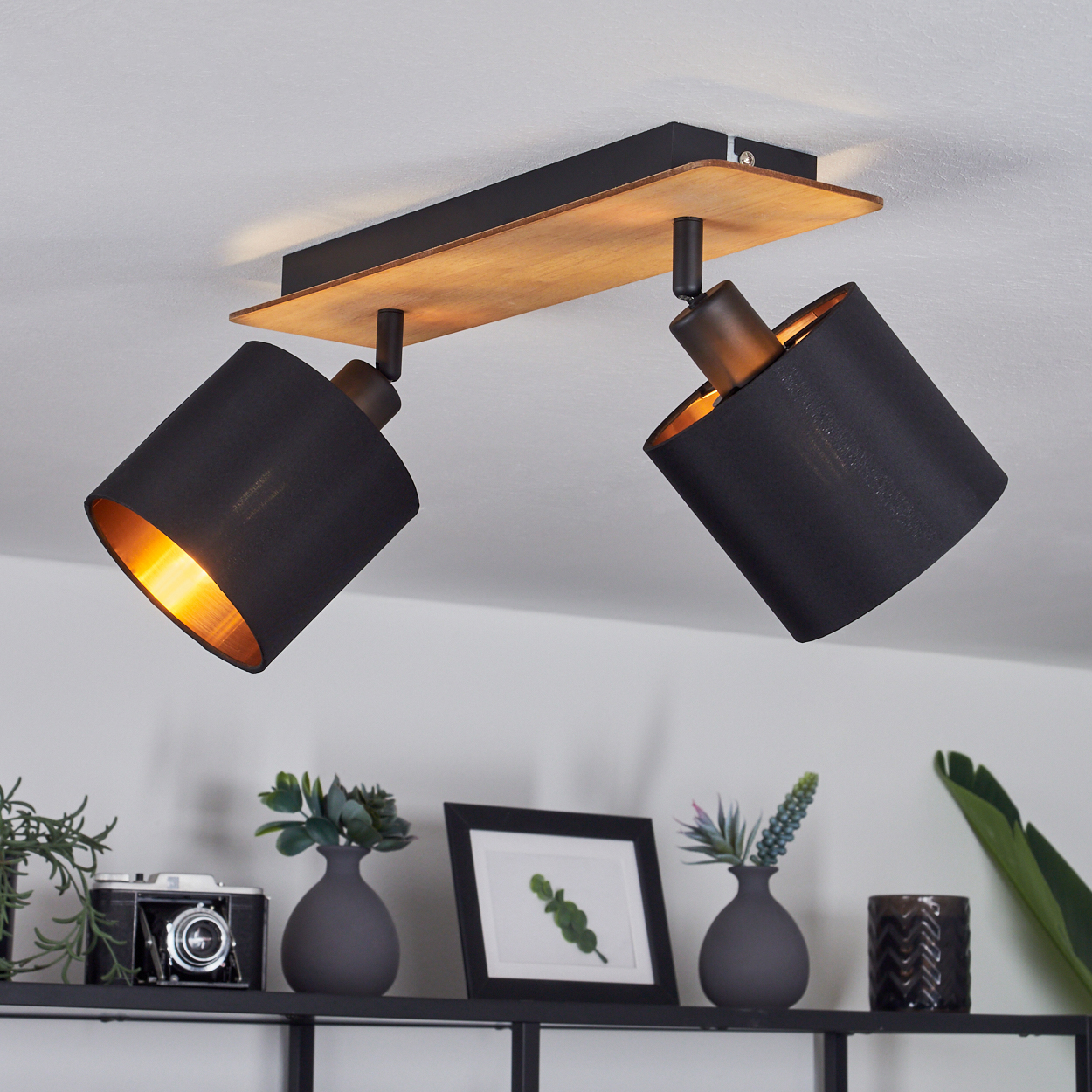 Zwei schwarze Lampenschirme mit Holzbalken-Deckenleuchte, beleuchtet.