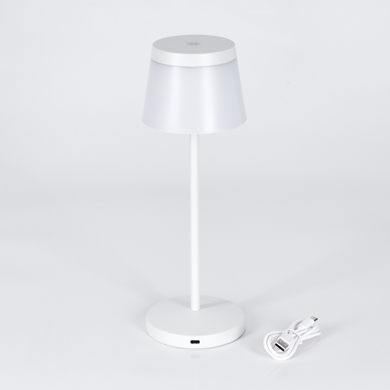 Eine weiße Nachttischlampe mit einem runden Fuß und einem USB-Kabel.