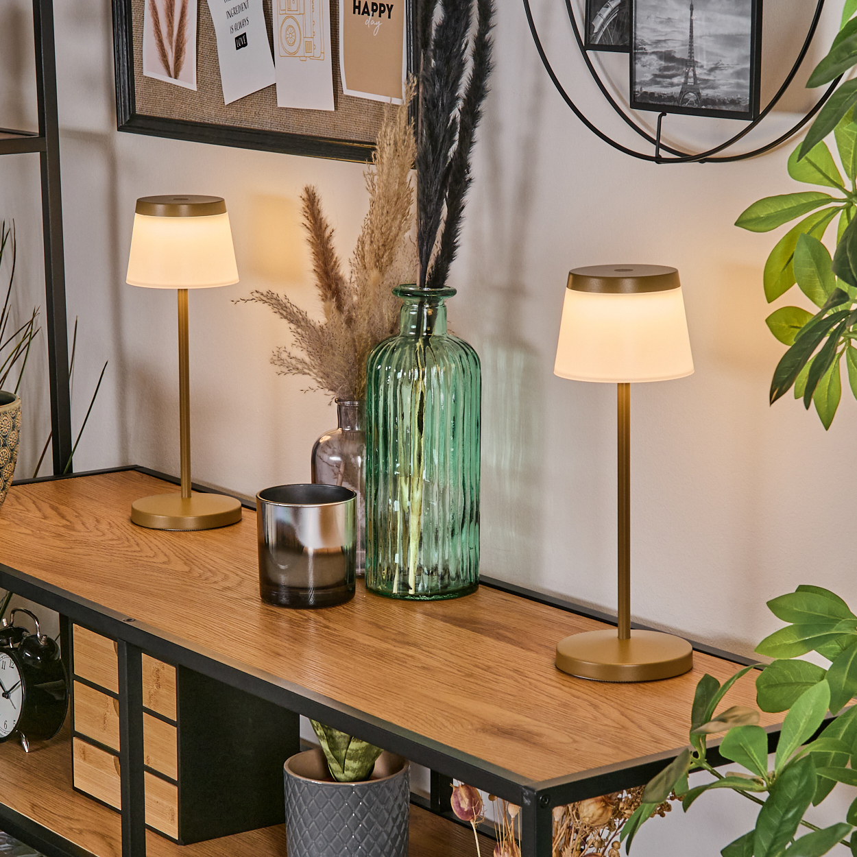 Zwei goldene Tischlampen auf einem Holzregal mit Dekorationsgegenständen.