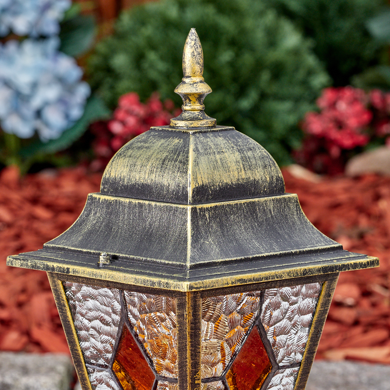 Ein goldener und schwarzer Laternenkopf mit Glasfenstern steht im Freien.