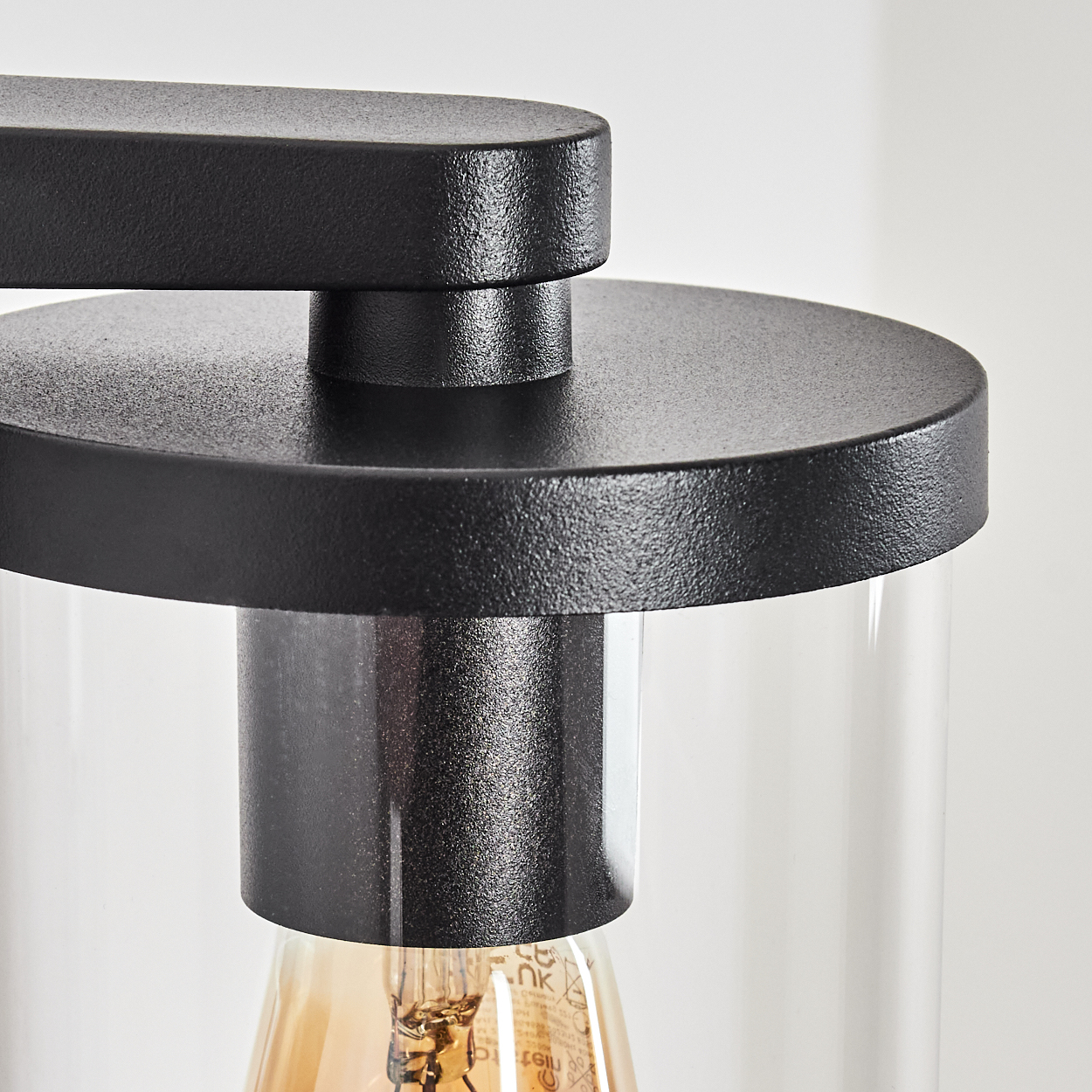 Nahaufnahme einer schwarzen Lampe mit Glaszylinder und Glühbirne.
