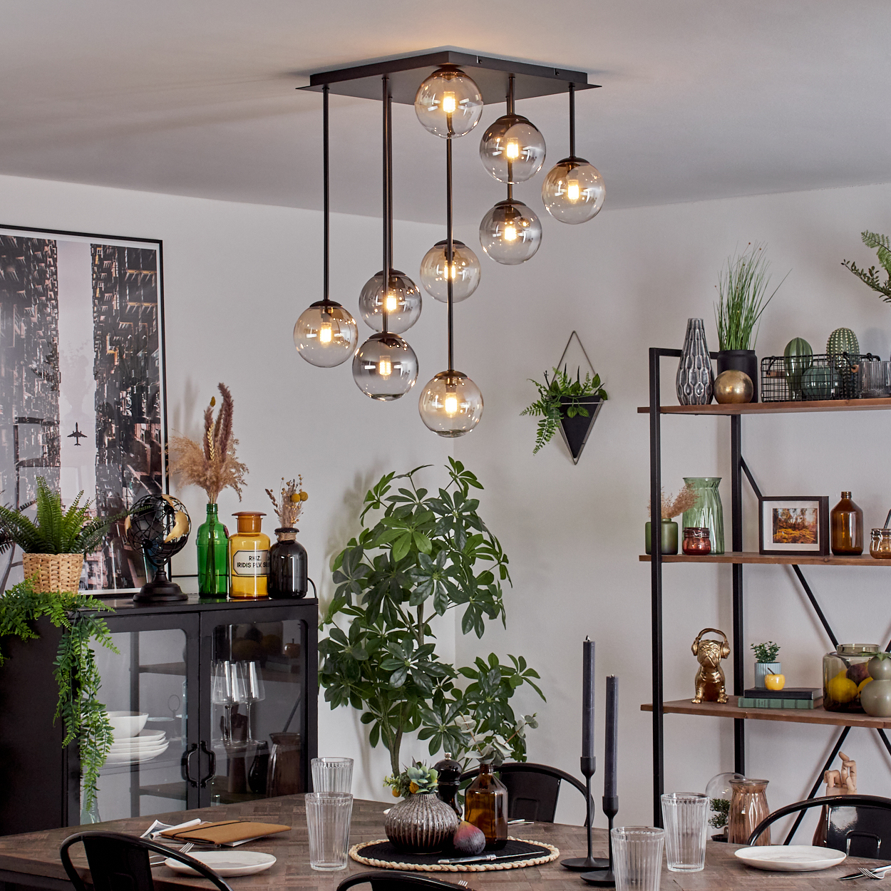 Ein Esszimmer mit einem Esstisch, Glaskerzenhaltern und einer Hängelampe.