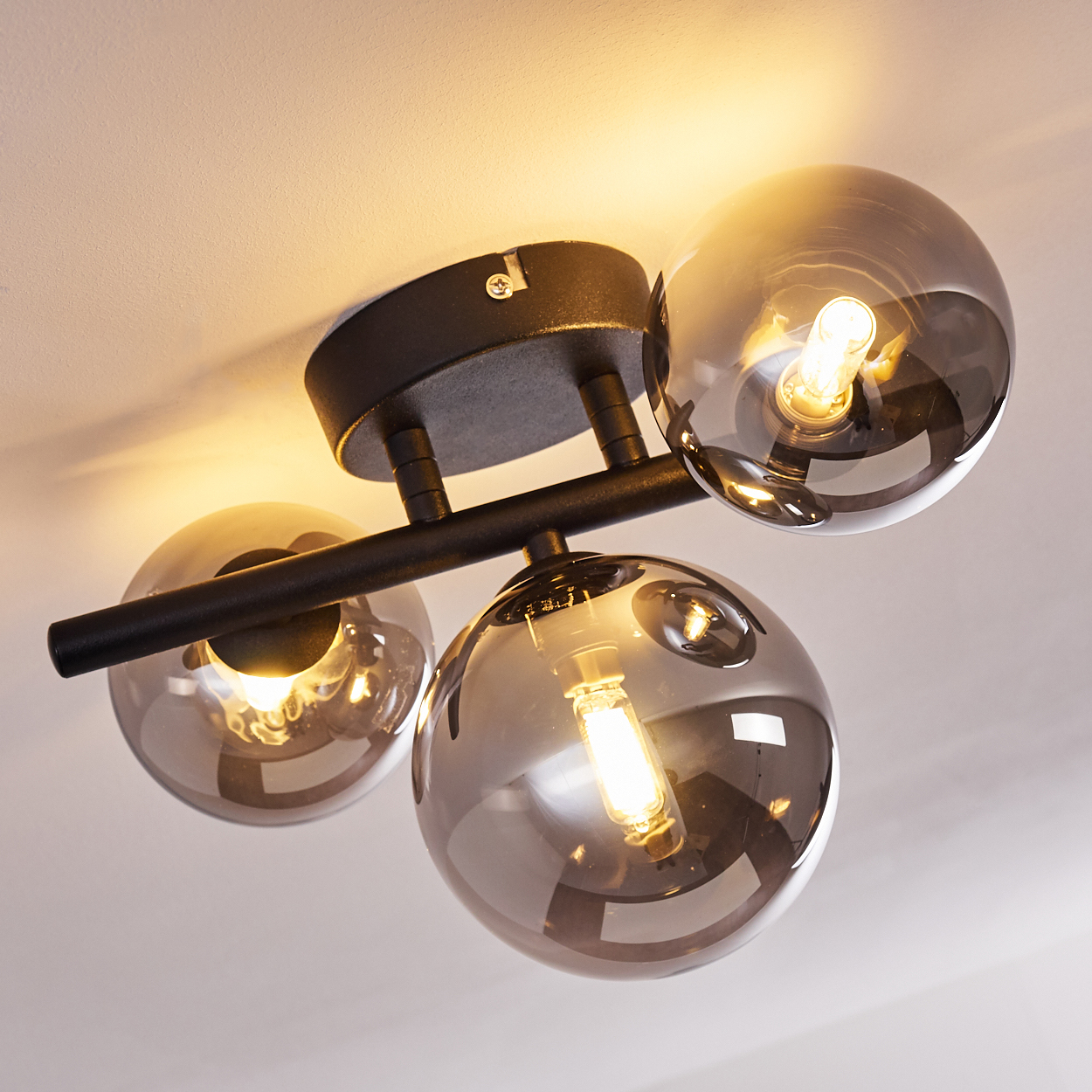 Moderne Deckenleuchte mit drei rauchglas Kugeln und schwarzen Metallakzenten.