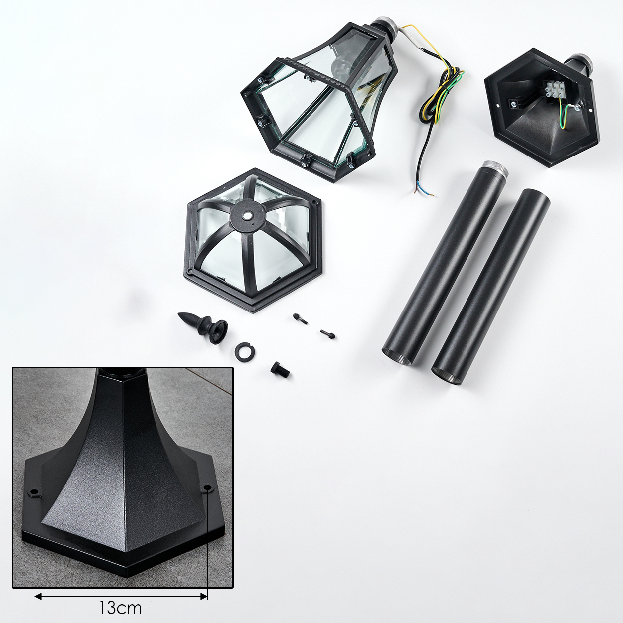 Zerlegte schwarze Laterne mit Glas und Metallteilen auf weißem Hintergrund.
