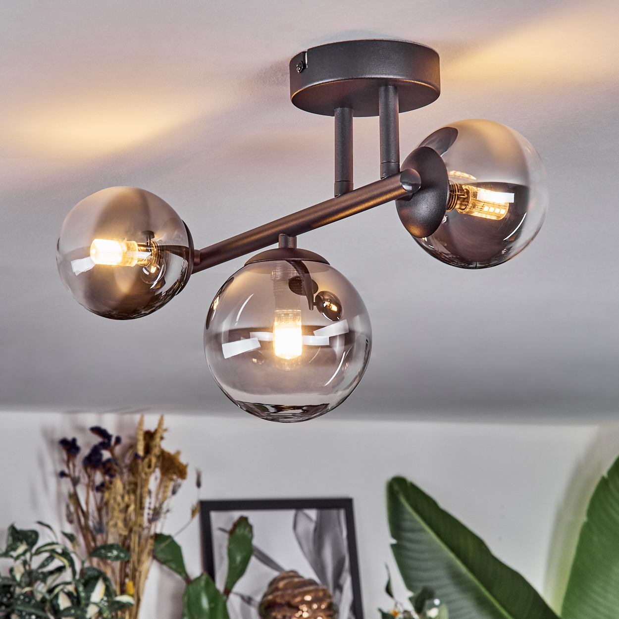 Drei rauchglas Lampen an dunklem Metallgestell, an Decke montiert.