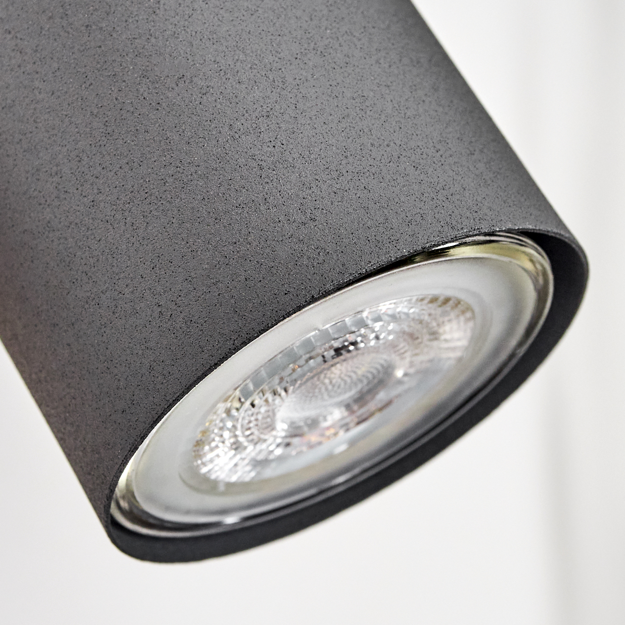 Nahaufnahme einer dunklen Zylinderlampe mit sichtbarem LED-Leuchtmittel und Glaseinsatz.