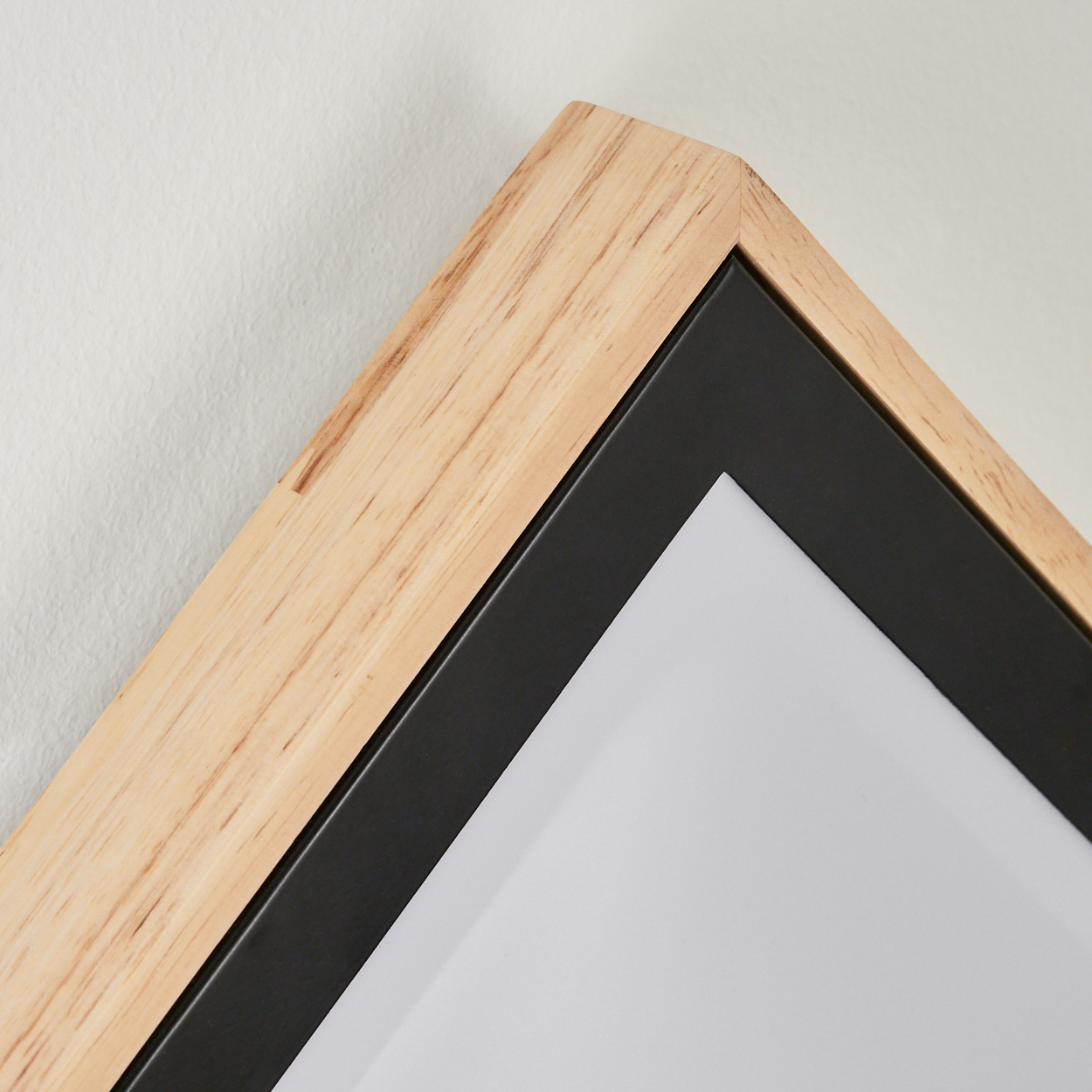 Holzrahmen mit schwarzem Einsatz vor weißer Wand.