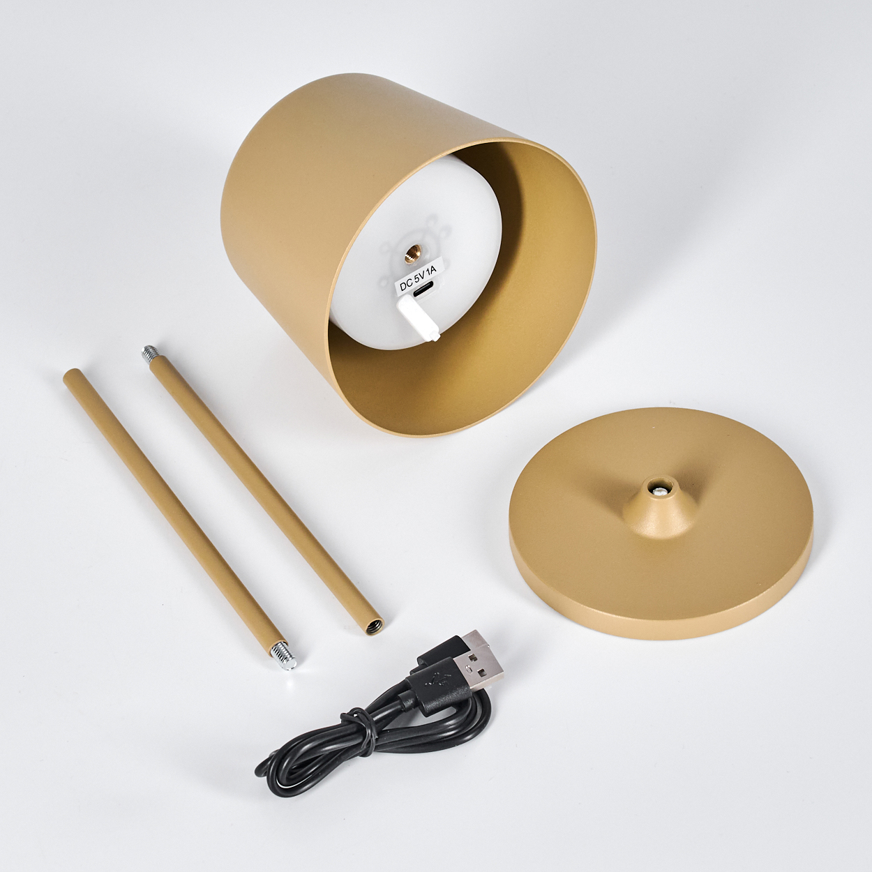 Ein goldener Lampenschirm, zwei Stangen, eine Basis und ein USB-Kabel auf weißem Grund.