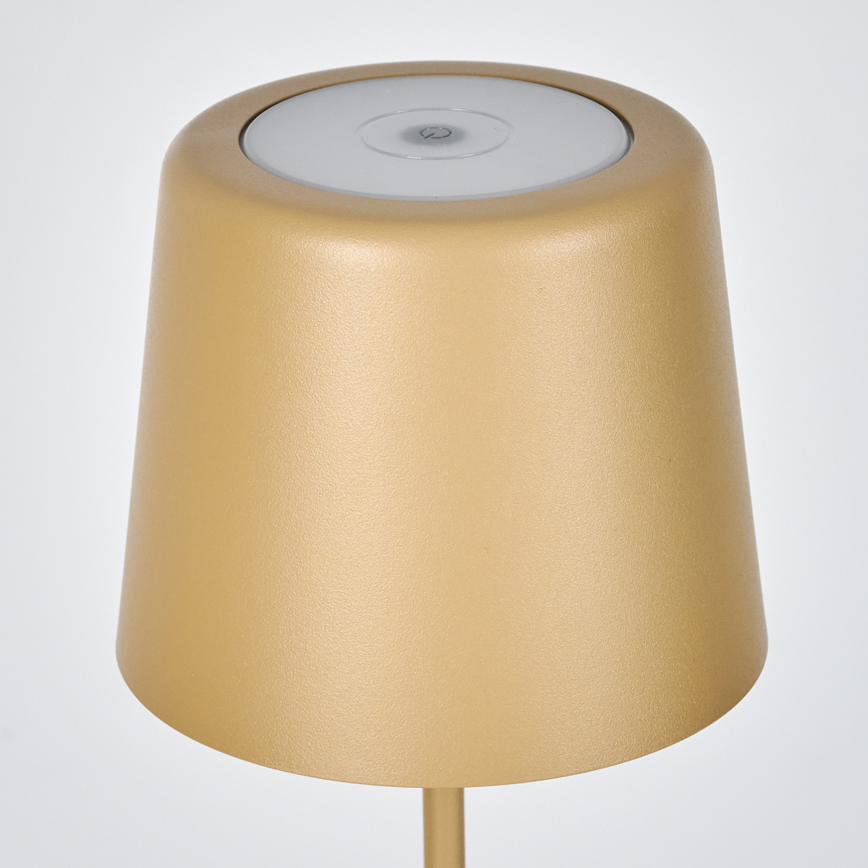 Goldene Lampe mit weißem oberen Teil auf hellem Hintergrund.