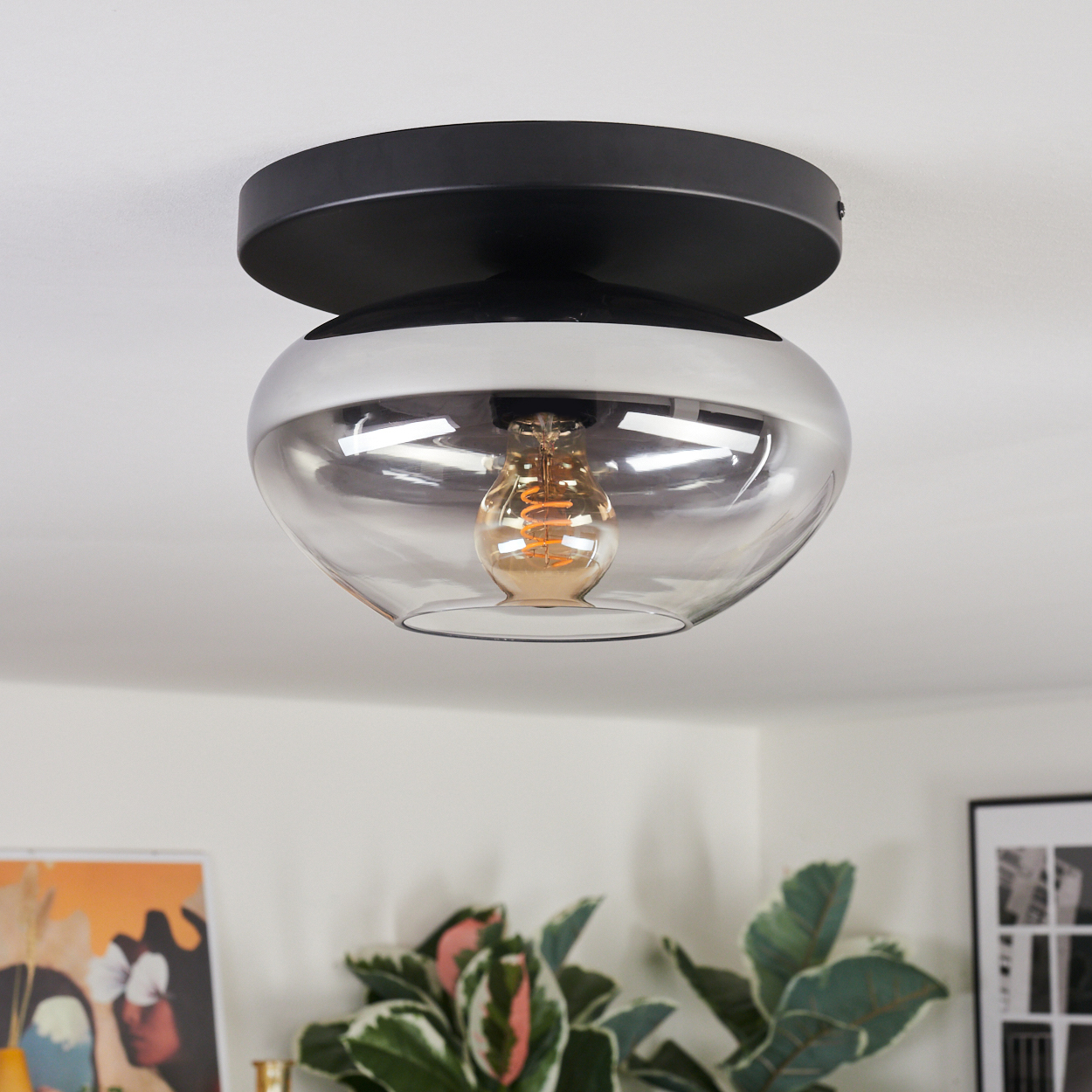 Moderne Deckenleuchte mit schwarzem Sockel, Glas und Glühbirne.