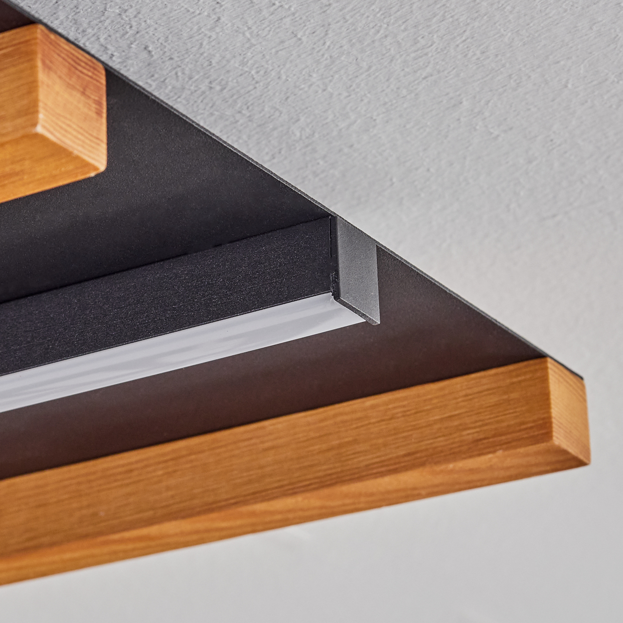 Ein moderner Deckenlampen-Detail mit Holz und schwarzem Metall.