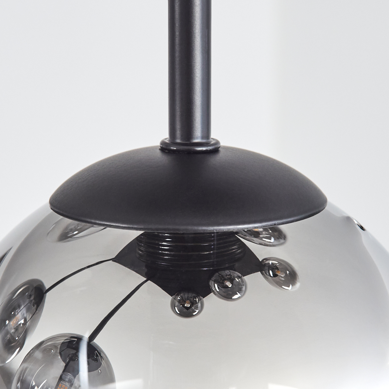 Nahaufnahme einer Rauchglas-Pendelleuchte mit schwarzen Metallakzenten.