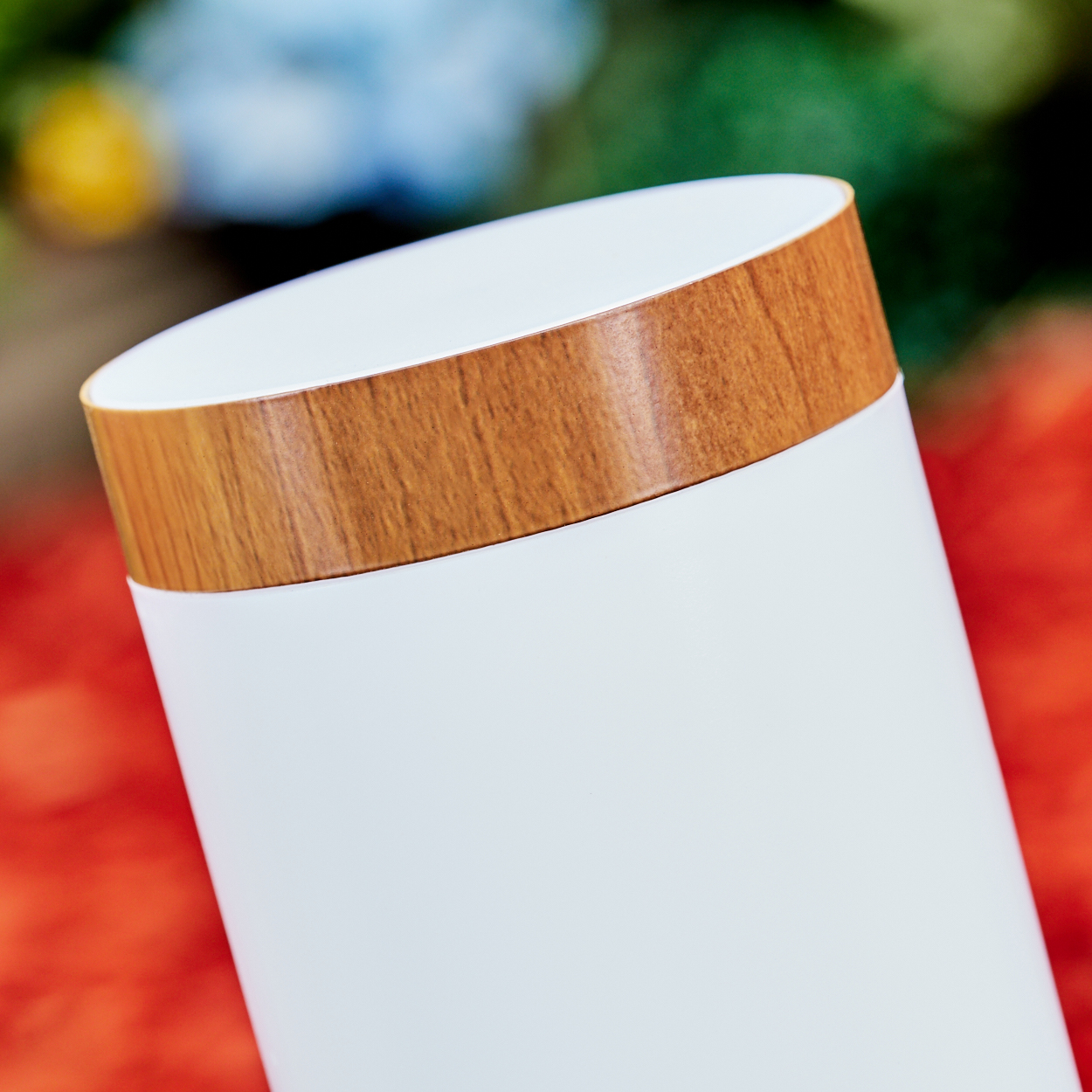 Ein weißer Becher mit Holzdekor am oberen Rand, auf rotem Hintergrund.