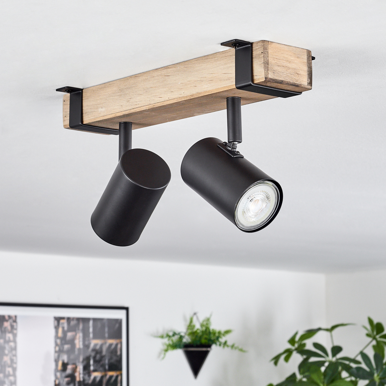 Holzbalkenlampe mit zwei schwarzen Spots an einer weißen Decke.