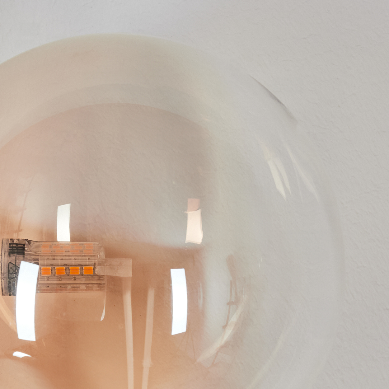 Nahaufnahme eines Glaskolbens mit LED-Streifen und orangen Lichtern.