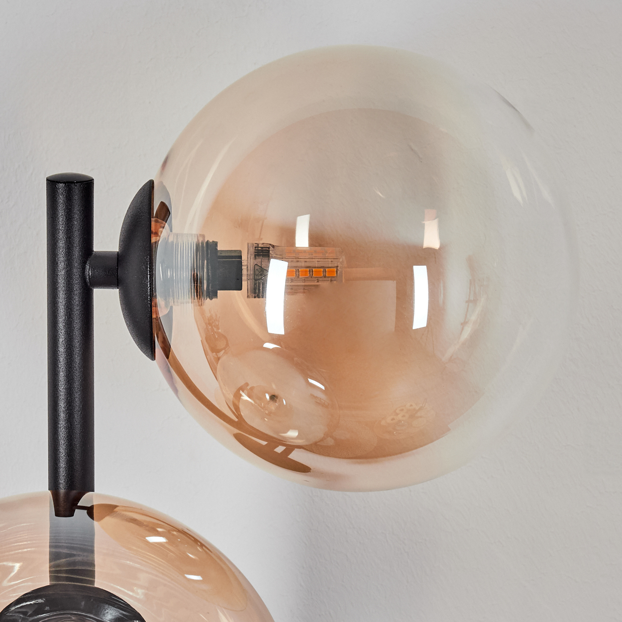 Eine Nahaufnahme einer Lampe mit einem schwarzen Ständer und einem bernsteinfarbenen Glaskolben.