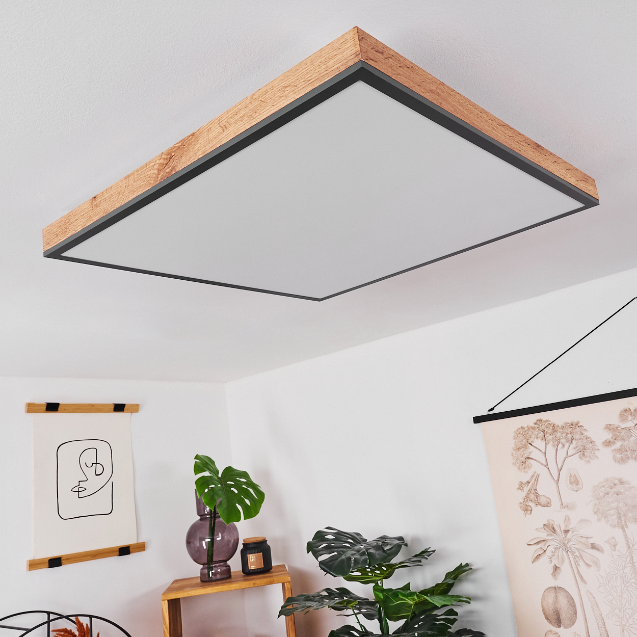 Moderne Deckenleuchte mit Holzrahmen und weißem Diffusor, daneben Pflanzen.
