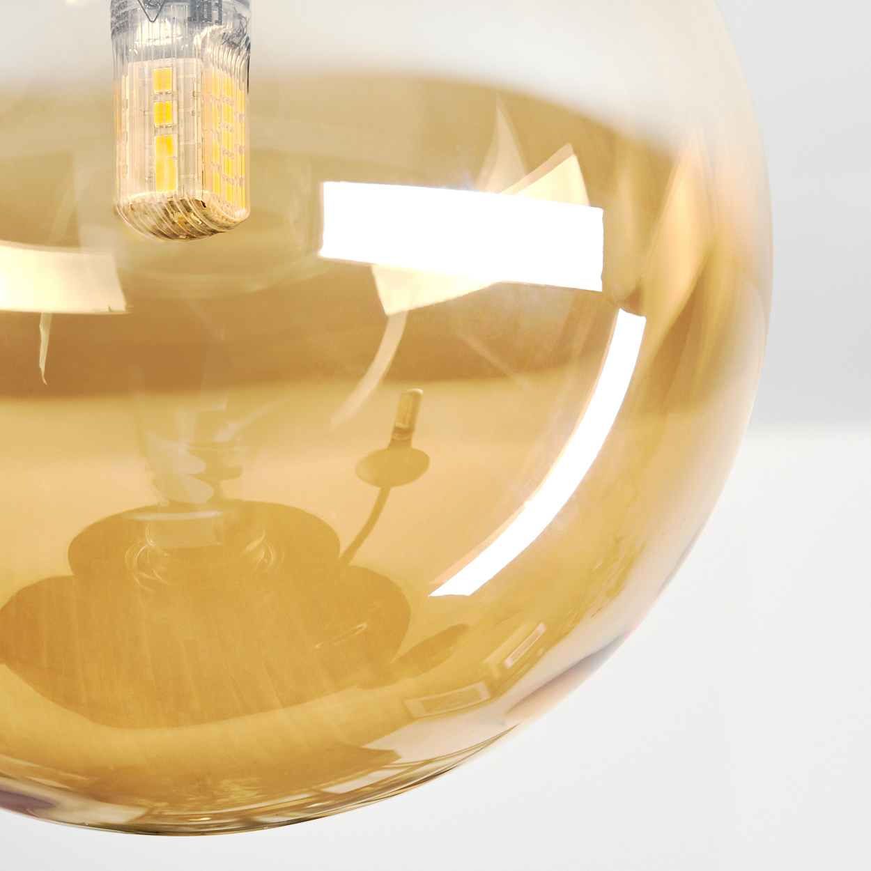 Eine bernsteinfarbene Glaskugel mit einer LED-Lampe, die innen reflektiert wird.