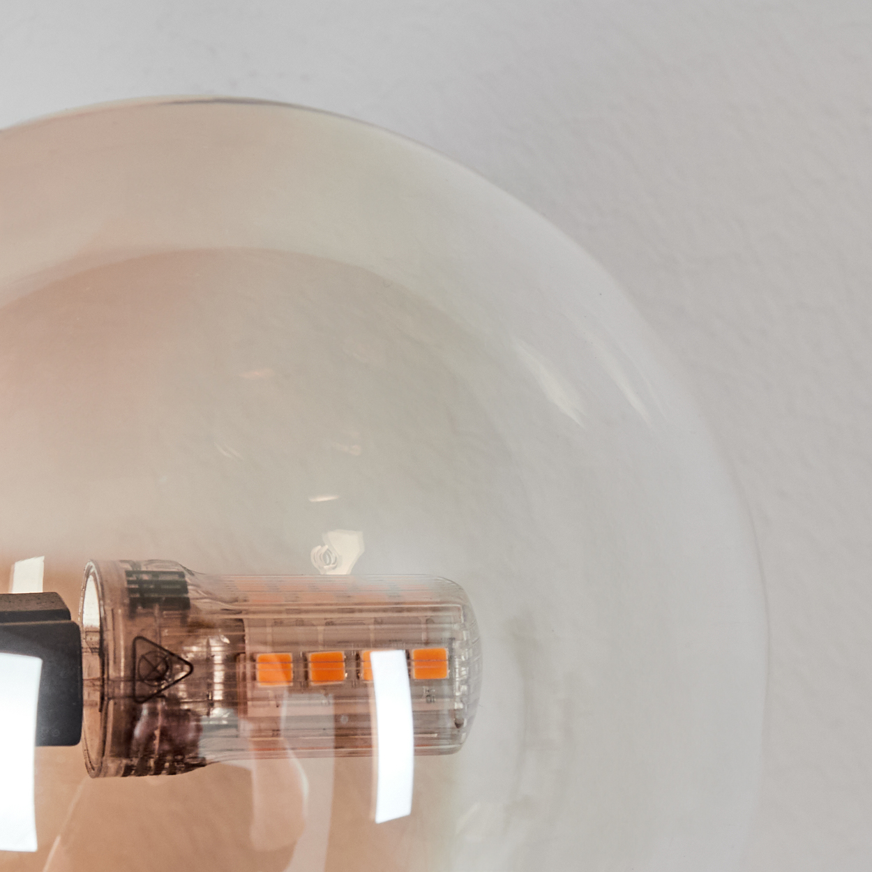 Nahaufnahme einer LED-Glühbirne mit transparentem Gehäuse und vier orangefarbenen Lichtern.