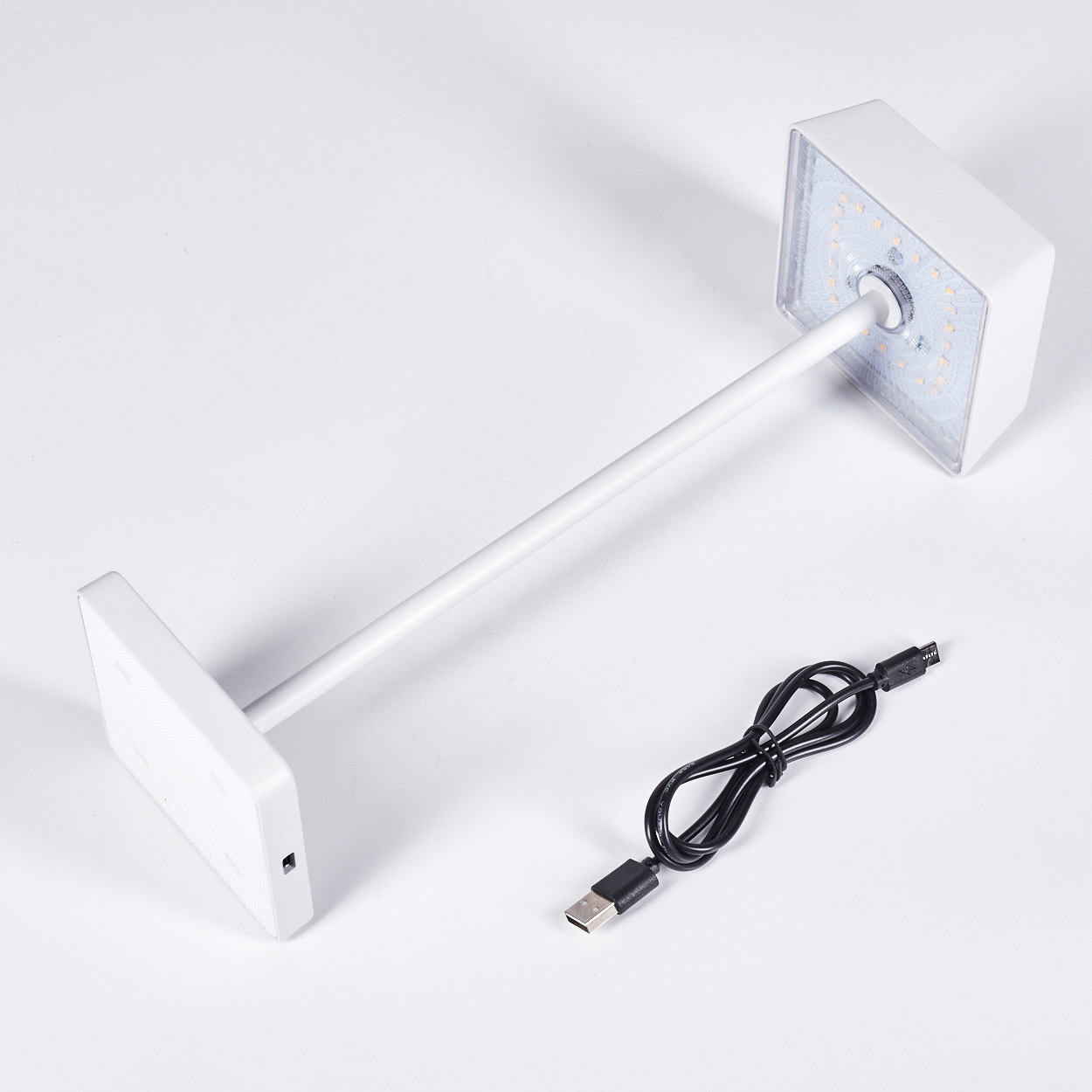 Ein weißer Tischlampenarm mit LED-Kopf und Ladekabel auf weißem Hintergrund.