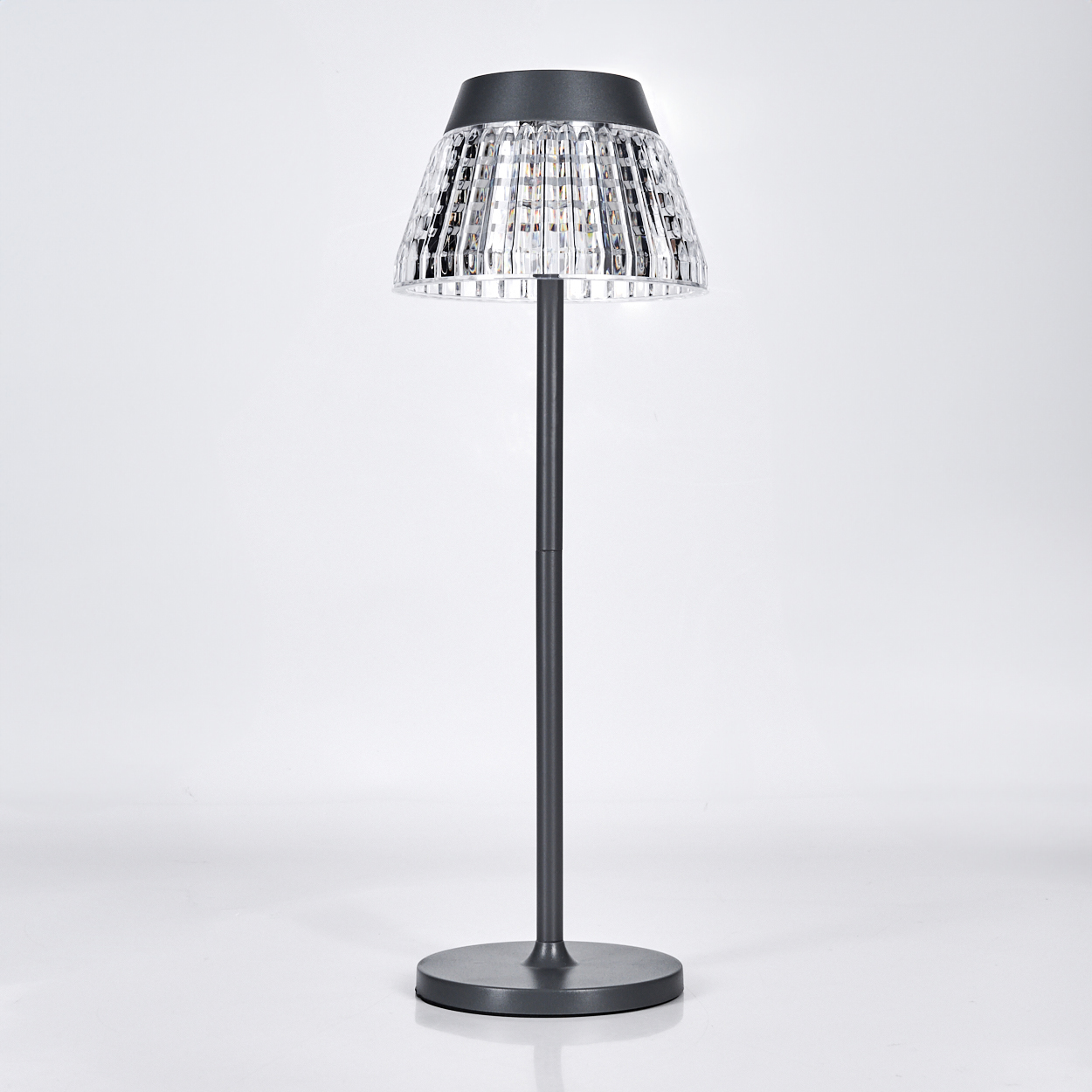 Eine dunkle Stehlampe mit einem Facettenschirm und einem runden Sockel.