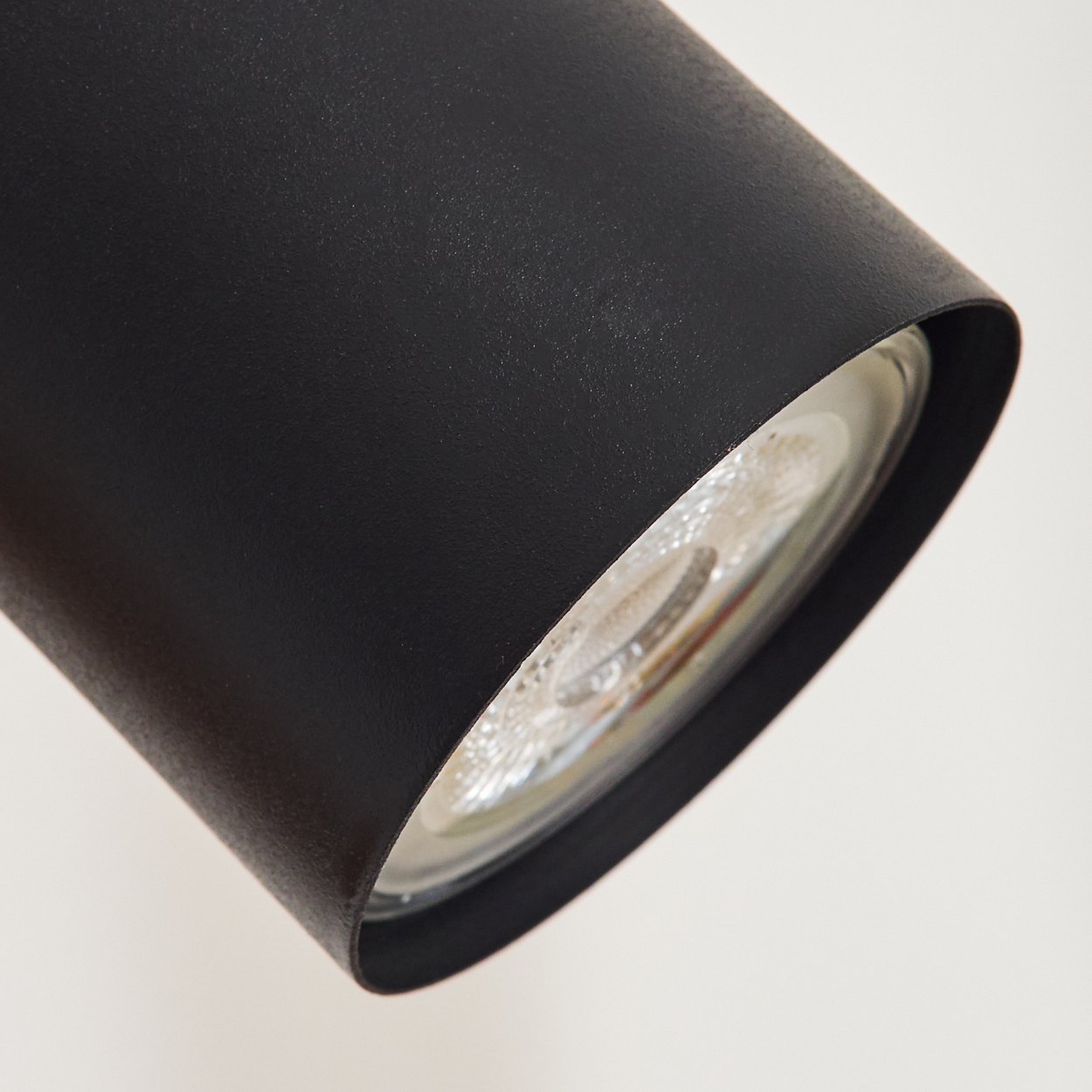 Nahaufnahme einer schwarzen Lampe mit sichtbarer Glühbirne und Reflektor.
