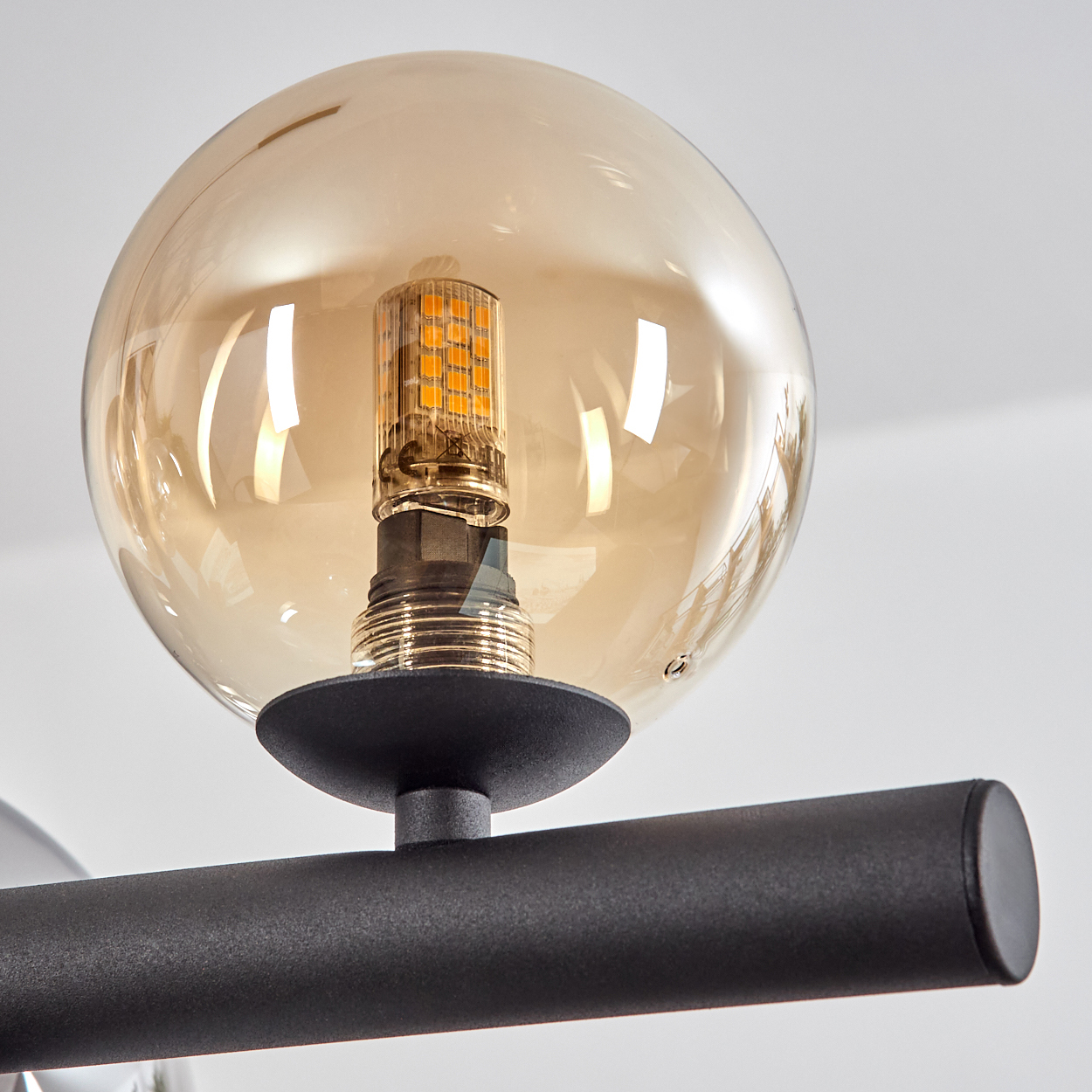 Eine bernsteinfarbene Glaskugel mit einer LED-Lampe und einem schwarzen Metallarm.