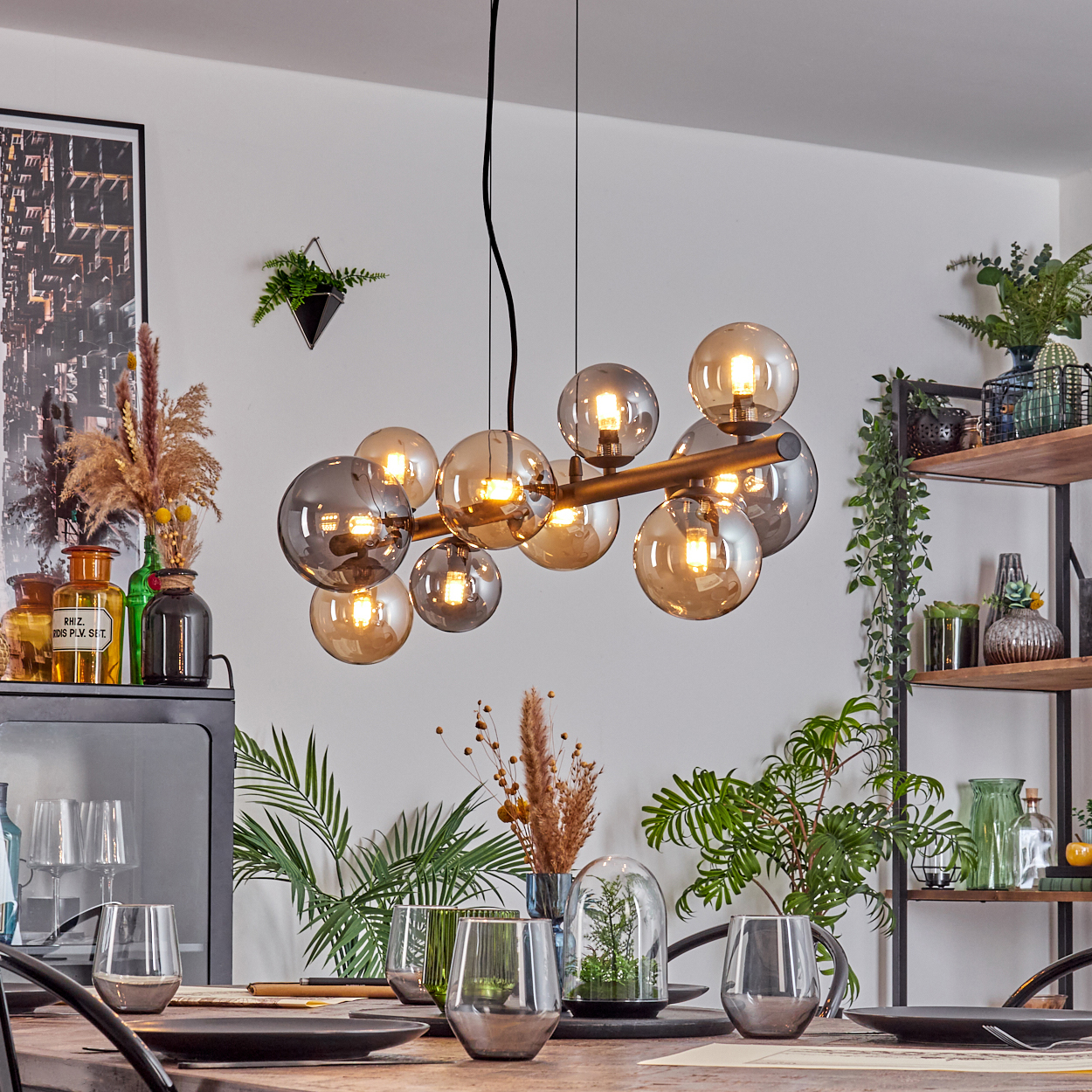 Esszimmer mit Hängelampe, Gläsern, Pflanzen und Regalen.
