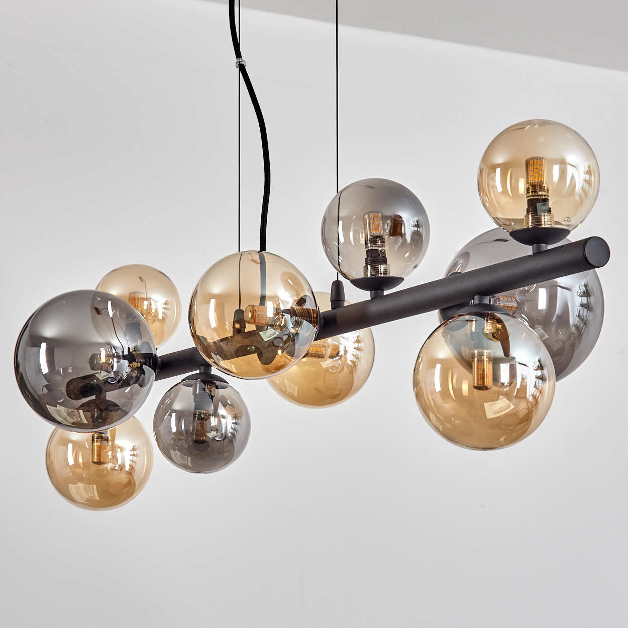 Ein moderner Kronleuchter mit schwarzen Metallarmen und bernsteinfarbenen und rauchgrauen Glaskugeln.
