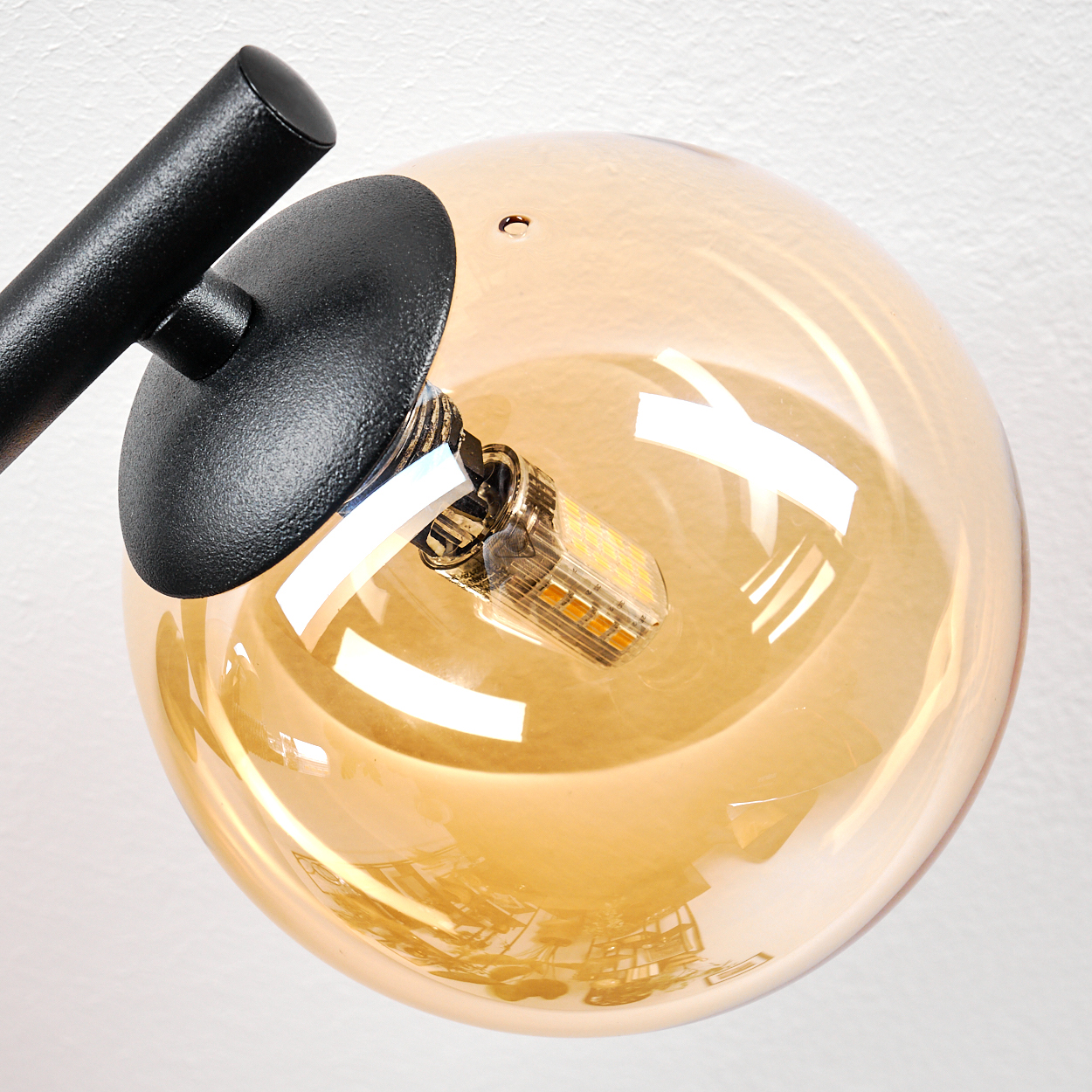 Nahaufnahme einer modernen Lampe mit bernsteinfarbenem Glas und schwarzem Arm.