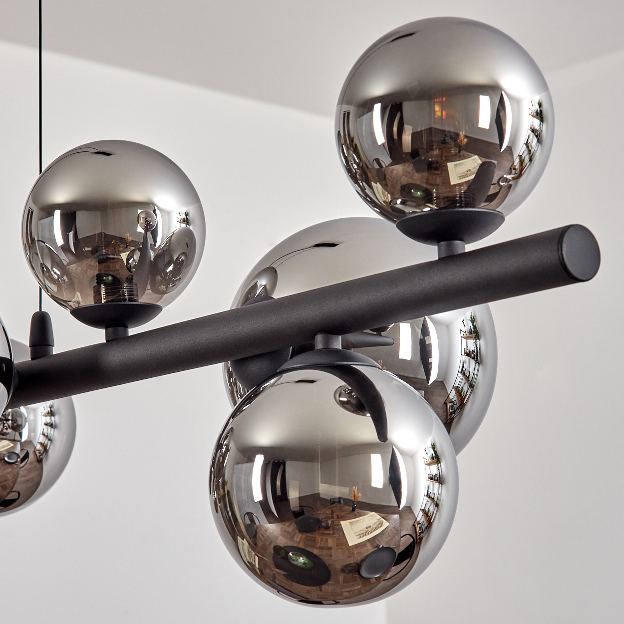 Moderne Pendelleuchte mit mehreren rauchglas-Kugeln an schwarzem Stab.