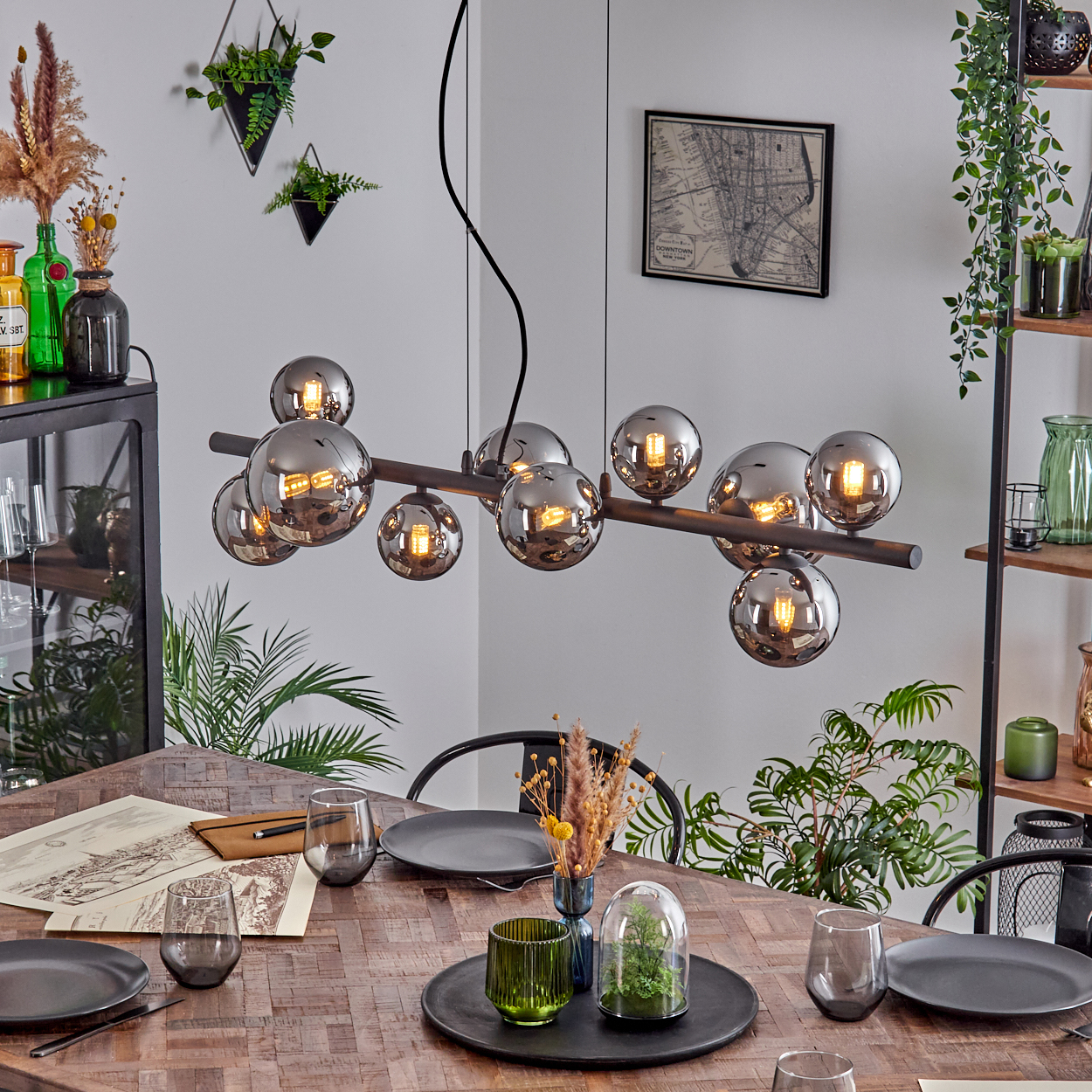 Esstisch mit moderner Hängeleuchte, Glaskugeln und Dekoration.