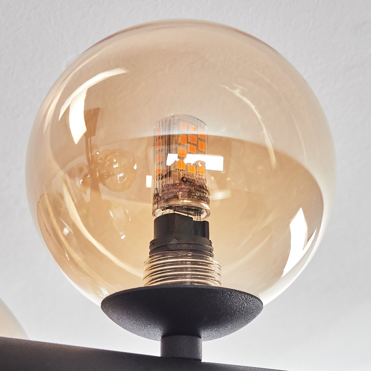 Eine bernsteinfarbene Glaskugel umschließt eine LED-Glühbirne mit orangefarbenen Dioden.