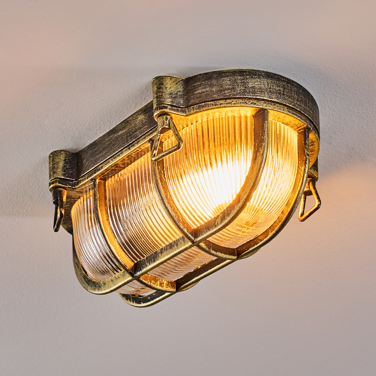 Ein antiker Wandleuchter mit goldfarbenem Metall und geripptem Glas.