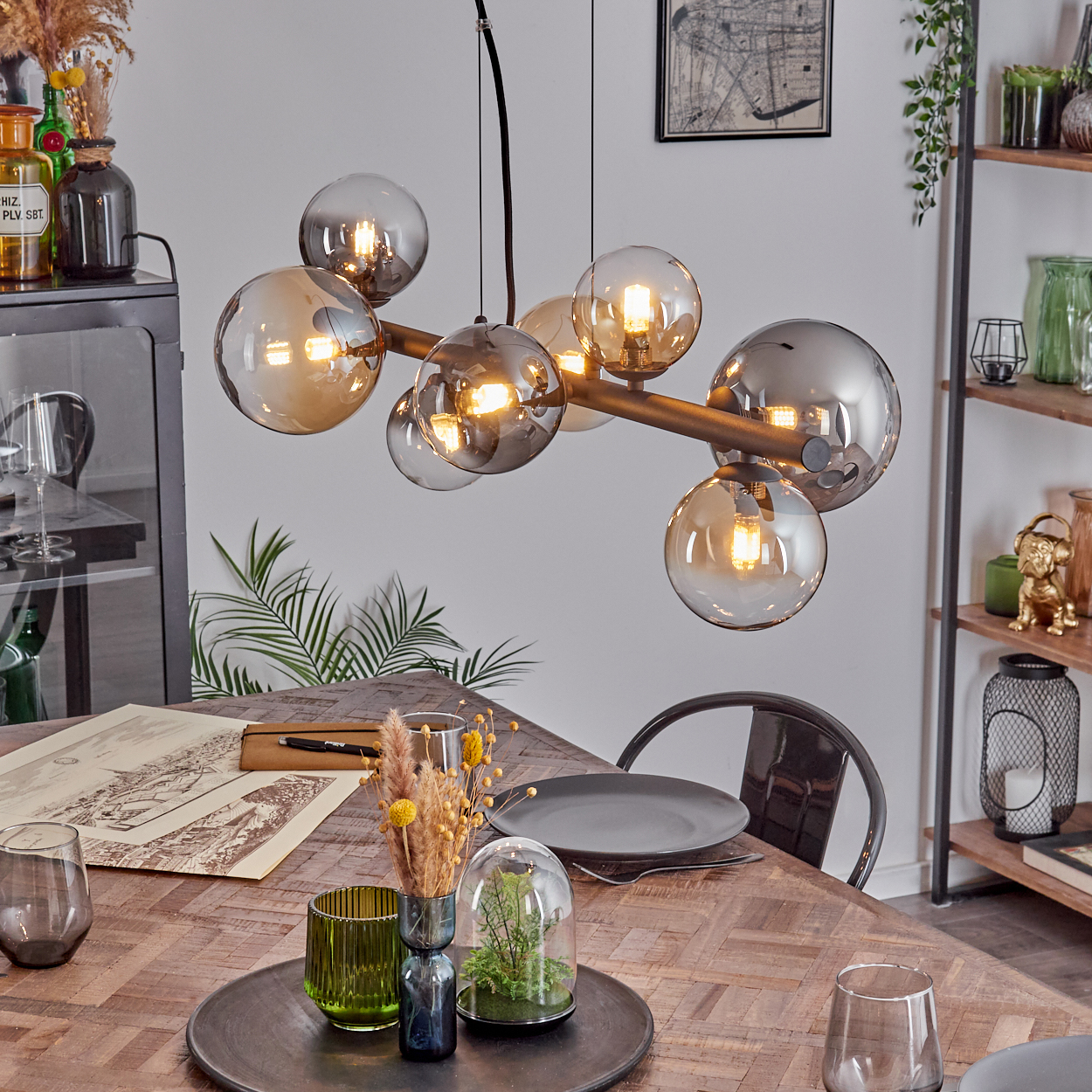 Eine moderne Hängeleuchte mit Rauchglas-Kugeln über einem Holztisch.