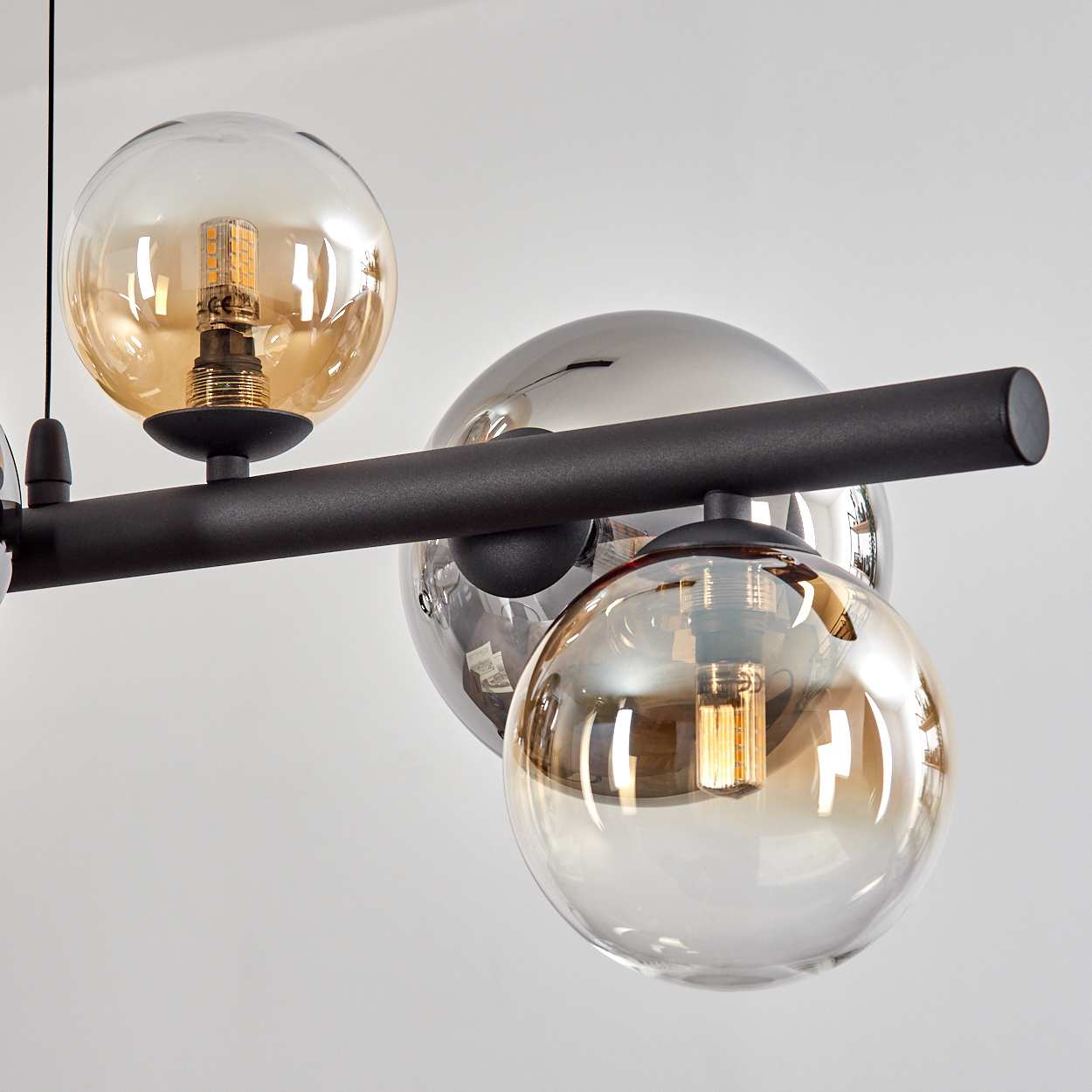 Eine moderne Lampe mit Glasglocken und LED-Birnen an einem schwarzen Balken.