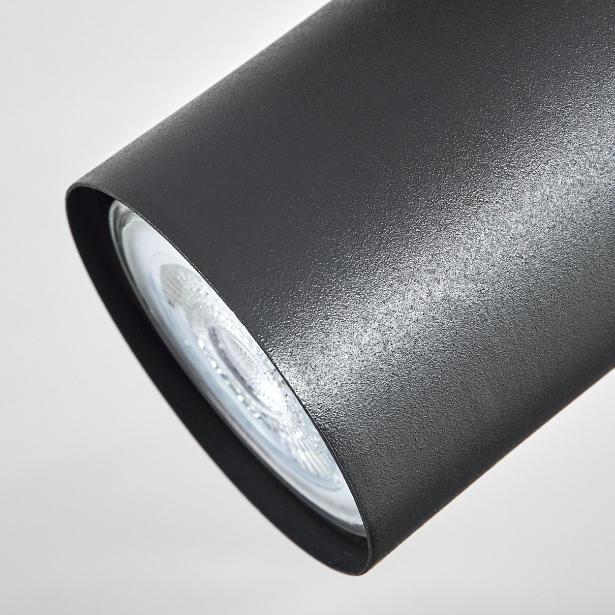 Nahaufnahme einer schwarzen zylindrischen Lampe mit silbernem Leuchtmittel.