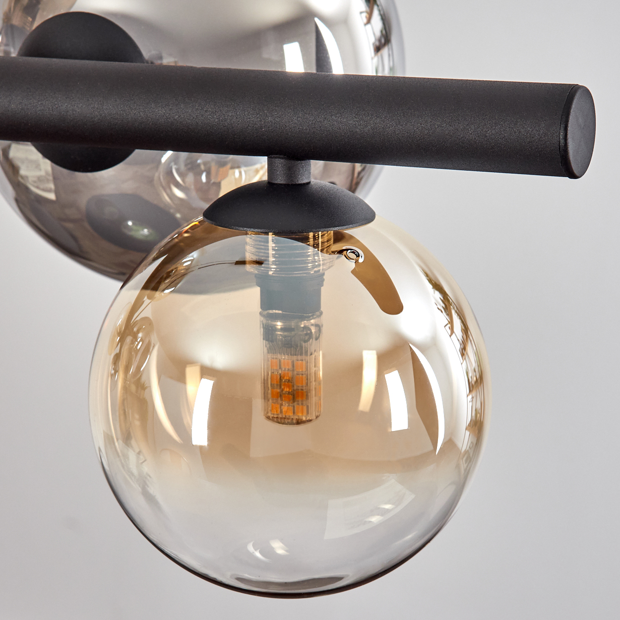 Moderne Lampe mit schwarzem Gestell und bernsteinfarbenen Glaskugeln.
