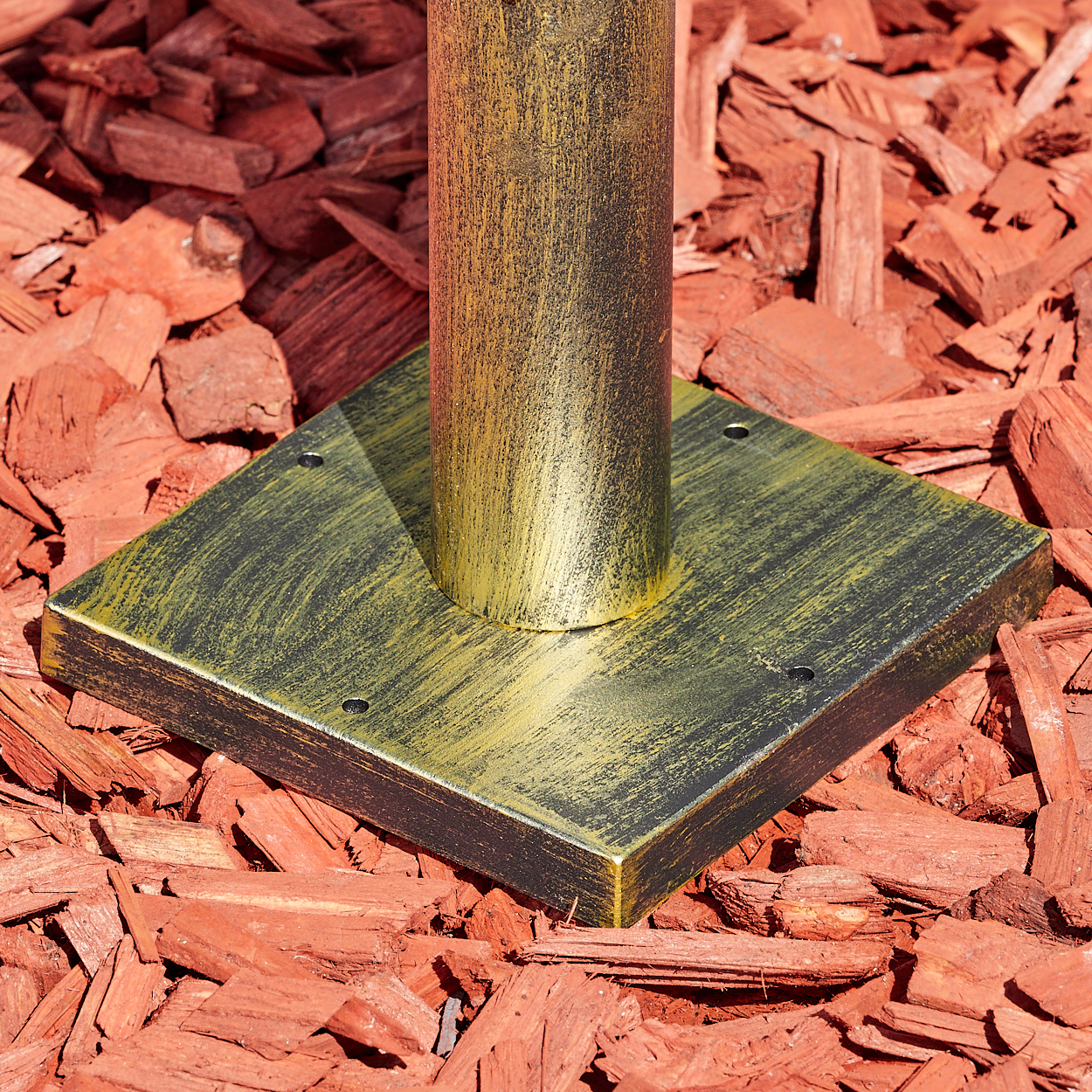 Goldener Sockel auf rotem Rindenmulch mit zylindrischer Stange.