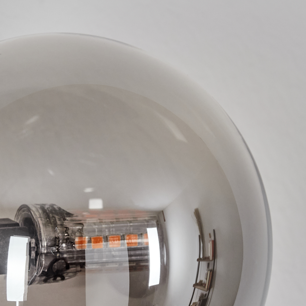 Nahaufnahme einer großen Edison-Glühbirne mit sichtbaren orangen LEDs und Reflexionen.