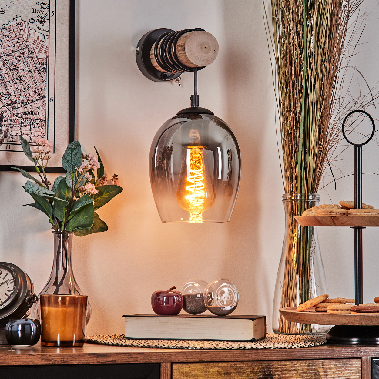 Ein Wandlicht mit Rauchglas, Glühbirne, Buch, Kerze, Apfel und Keksen.