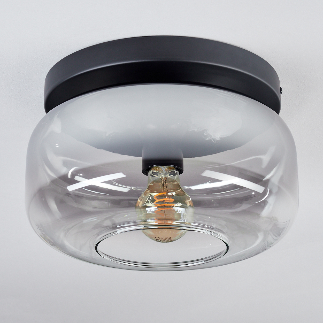 Schwarzer Deckenlampensockel mit transparenter Glasglocke und sichtbarer Glühbirne.