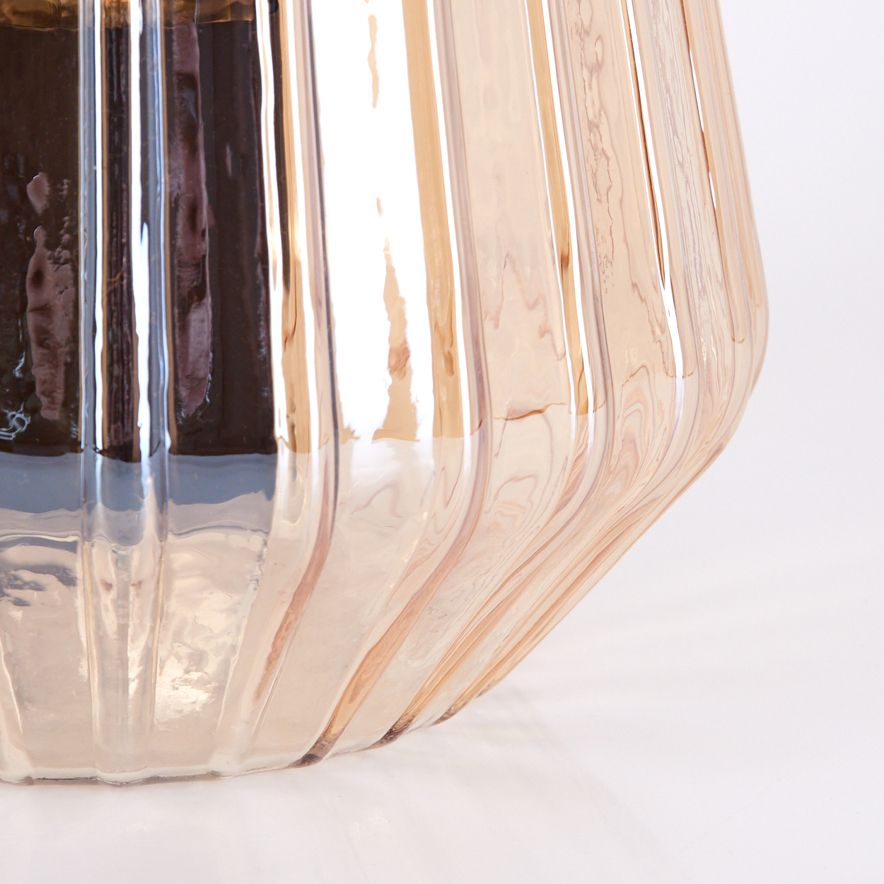 Ein nahaufnahme eines roségoldenen, gerippten Glasbehälters.