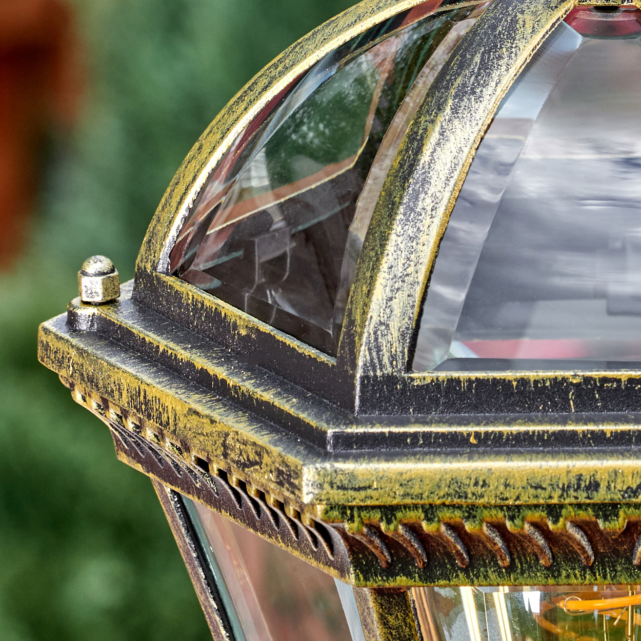 Detailaufnahme einer goldenen Laterne mit Glasfenstern und grünem Hintergrund.