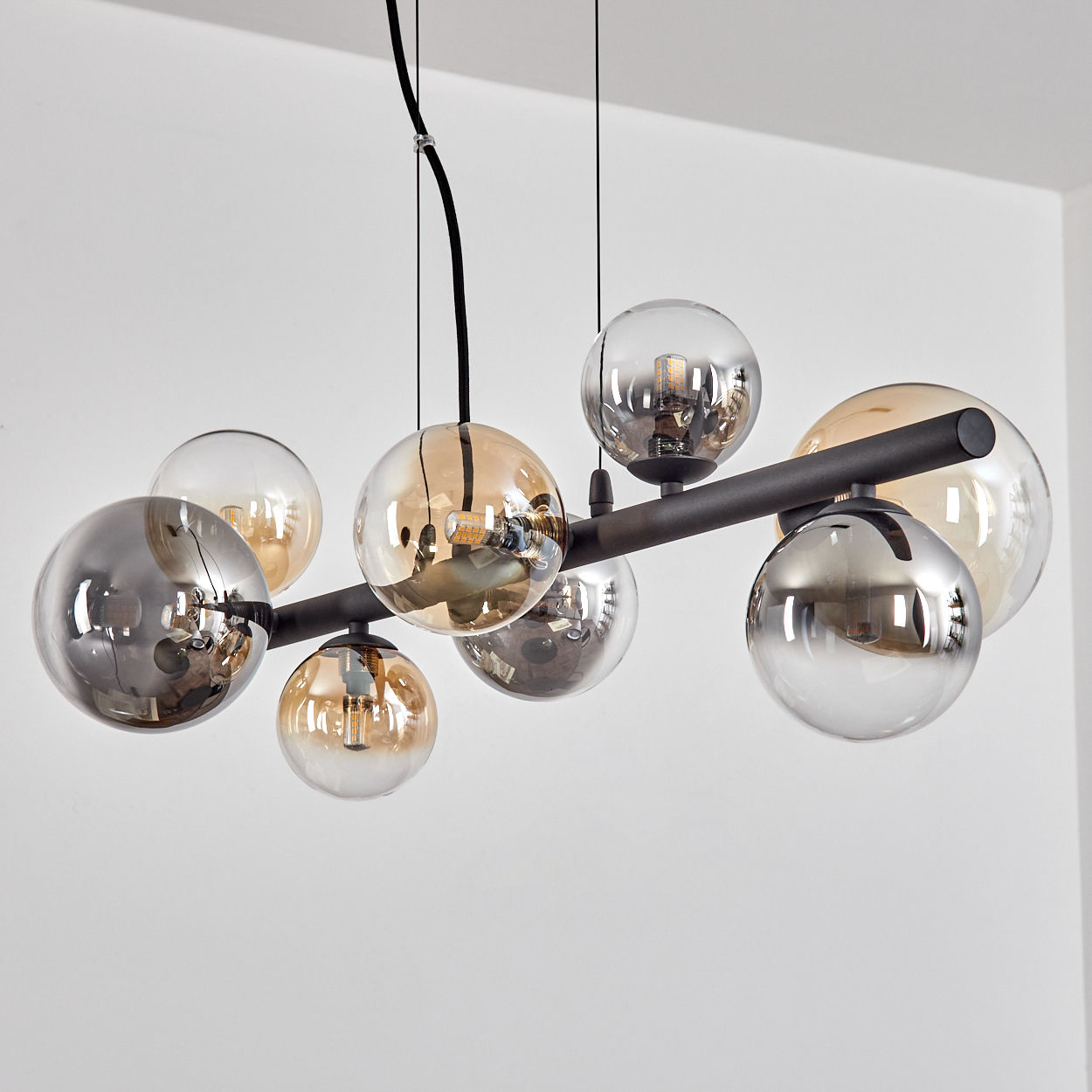 Eine moderne Lampe mit schwarzen Metallarmen und Glaskugeln in Grau und Bernstein.