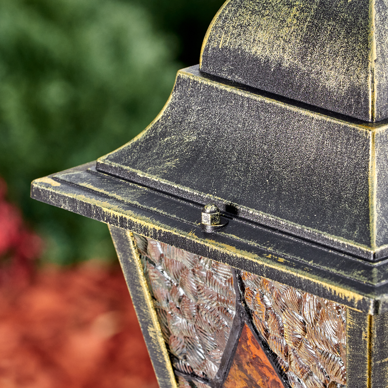 Eine dunkle Laterne mit goldener Patina und strukturiertem Glas.