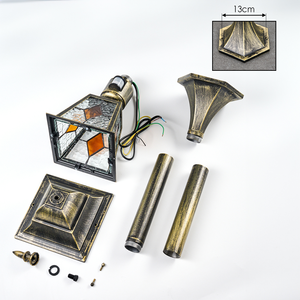 Teile einer bronzefarbenen Lampe mit Glasfenstern und Zubehör auf weißem Hintergrund.