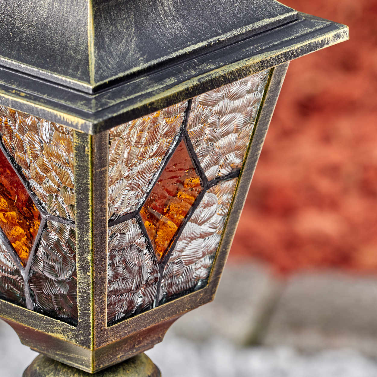 Eine goldene Laterne mit strukturiertem Glas und bernsteinfarbenen Akzenten.