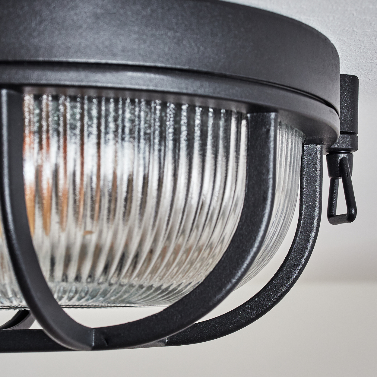 Eine schwarze Lampe mit geripptem Glas und Metallschutzgitter.